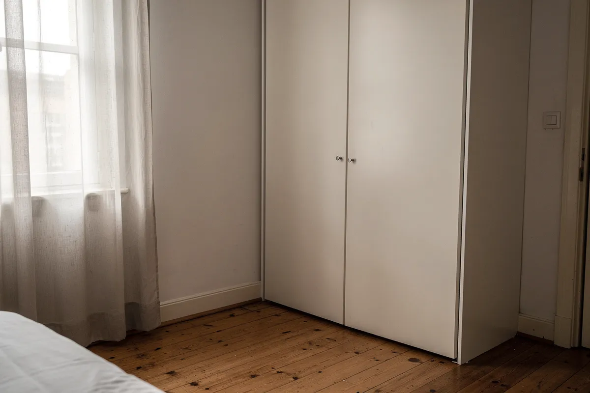 Rincón de dormitorio con armario empotrado y cortina que filtra la luz
